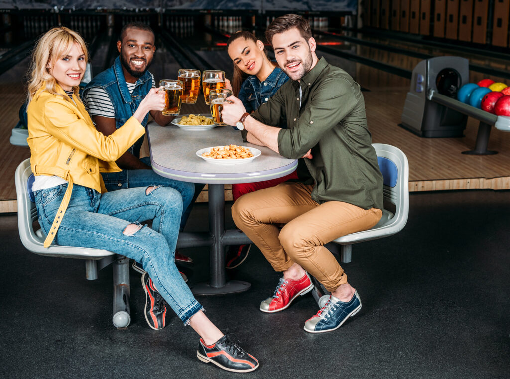 group of friends clinking mugs of beer at bowling club in front